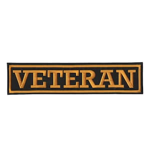 May include: A rectangular embroidered patch featuring a black background with a gold border and the word VETERAN stitched in gold capital letters. The design is centered with a clean, bold font style and a thick, uniform gold outline frame.