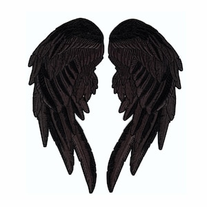 Peut inclure: Deux écussons d'ailes brodées noires avec des détails de plumes. Les écussons sont symétriques, chaque aile reflétant l'autre. Les ailes sont posées sur un fond blanc, mettant en valeur la couleur sombre et le design complexe.