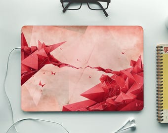 Könnte beinhalten: Ein Laptop mit einem pinkfarbenen und roten geometrischen Design auf der Abdeckung. Das Design zeigt eine große rote geometrische Form in der Mitte der Abdeckung, umgeben von kleineren roten geometrischen Formen. Der Hintergrund der Abdeckung ist hellrosa.