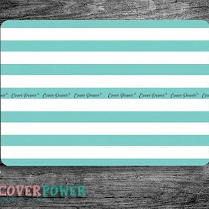 May include: Rectangular teal and white striped product with rounded corners. The words "Cover Power" are printed repeatedly along the top of the product. The product is on a wooden surface.