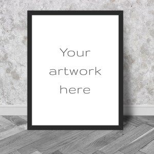 K&ouml;nnte beinhalten: Ein schwarzer gerahmter Druck mit dem Text "Your artwork here" auf wei&szlig;em Hintergrund. Der Rahmen lehnt an einer strukturierten grauen Wand und einem grauen Holzboden.