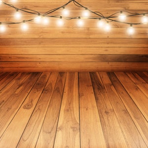 May include: A wooden floor with a warm brown hue, illuminated by a string of white lights hanging from a wooden ceiling.