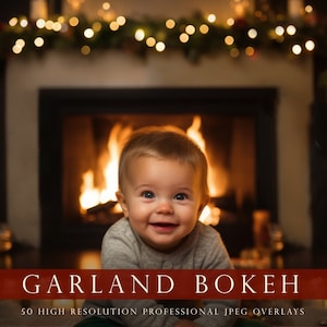 May include: A baby smiles at the camera while sitting in front of a fireplace with a garland of lights above it.