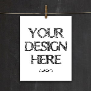 以下が含まれることがあります： 白い紙に黒い手書きの文字で「YOUR DESIGN HERE」と書かれている。紙は木製の洗濯ばさみで洗濯ロープにかけられている。
