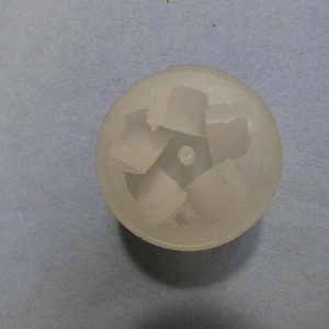 May include: A translucent, white plastic object with a circular shape and a central hole. The object has a star-like design with five sections cut out, giving it a unique, open appearance. The object is set against a light blue background.