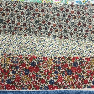 May include: A collection of six fabric swatches featuring various floral designs. The swatches are stacked vertically, starting with a pink and white floral pattern, followed by a blue and white floral pattern, a brown and white geometric pattern, a white and yellow floral pattern, a red and white floral pattern, and finally a blue and white floral pattern.