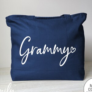 May include: A navy blue tote bag with the word 'Grammy' in white cursive lettering with a small white heart after the 'y'.