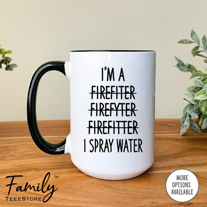 Op de afbeelding: Een witte keramische mok met een zwarte rand en handvat. De mok heeft zwarte tekst met de tekst "I'm a Firefighter Firefyter Firefitter I Spray Water".