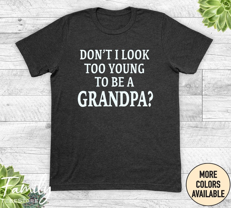 May include: Dark grey t-shirt with white text that reads "Don't I look too young to be a Grandpa?"