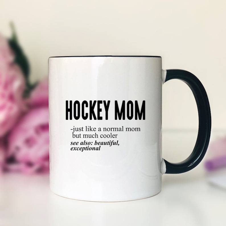 Puede incluir: Taza de caf&eacute; de cer&aacute;mica blanca con borde y asa negros. La taza tiene texto negro que dice "HOCKEY MOM - just like a normal mom but much cooler see also: beautiful, exceptional"