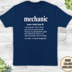 May include: A navy blue t-shirt with white text that reads "mechanic" and a definition of the word. The definition is: "noun/muh-kan-ik/ -someone who does precision guesswork based on unreliable data provided by those of questionable knowledge see also: wizard, magician"