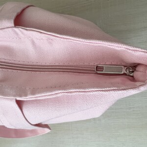 K&ouml;nnte beinhalten: Eine rosa Canvas-Tragetasche mit Rei&szlig;verschluss. Der Rei&szlig;verschluss ist silberfarben und hat einen Schieber.