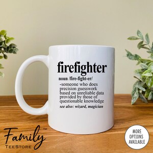 May include: White ceramic coffee mug with a black graphic that reads "firefighter" and a definition of the word. The mug has a black handle and the text "Family Teestore" is printed on the bottom of the mug.