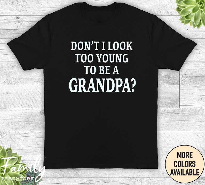 May include: Black t-shirt with white text that reads "Don't I look too young to be a grandpa?"