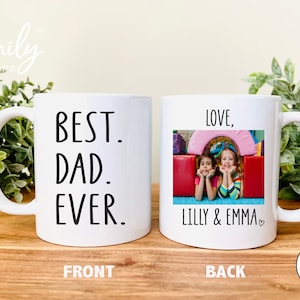 May include: White ceramic mug with black text that reads "BEST. DAD. EVER." on the front. The back of the mug has a photo of two young girls with the text "LOVE, LILLY & EMMA" below the photo.