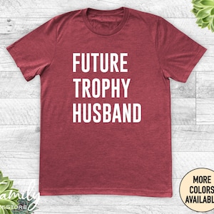 May include: Red t-shirt with the text "FUTURE TROPHY HUSBAND" in white lettering.