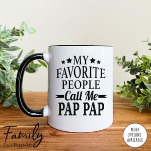 May include: White ceramic coffee mug with a black handle and black rim. The mug has black text that reads "My Favorite People Call Me Pap Pap".