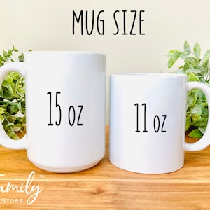 Pu&ograve; includere: Due tazze di ceramica bianca di diverse dimensioni. La tazza pi&ugrave; grande &egrave; etichettata "15 oz" e quella pi&ugrave; piccola "11 oz". Il testo "MUG SIZE" &egrave; sopra le tazze. Il logo Family TeeStore &egrave; in basso.