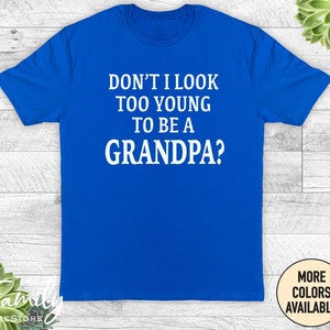 May include: A royal blue t-shirt with white text that reads "Don't I look too young to be a grandpa?"