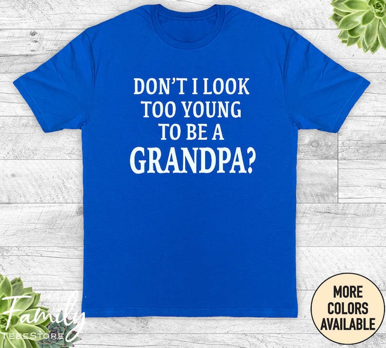 May include: A royal blue t-shirt with white text that reads "Don't I look too young to be a grandpa?"