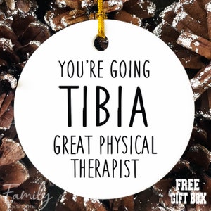 May include: White round ceramic ornament with black text that reads "You're going to be a great physical therapist". The text "TIBIA" is in large bold letters.