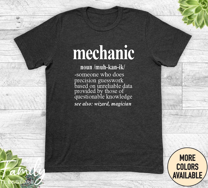 May include: A dark grey t-shirt with a white graphic that defines the word "mechanic" as someone who does precision guesswork based on unreliable data provided by those of questionable knowledge. The graphic also says "see also: wizard, magician".