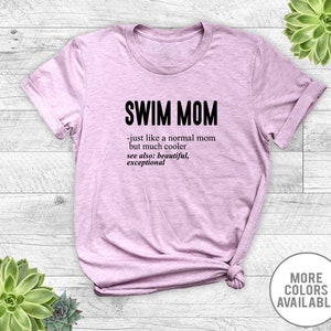 May include: A light purple t-shirt with the text "SWIM MOM - just like a normal mom but much cooler see also: beautiful, exceptional" printed in black.
