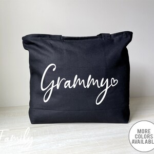K&ouml;nnte beinhalten: Schwarze Stofftasche mit dem Wort "Grammy" in wei&szlig;er Kursivschrift mit einem kleinen Herz daneben.