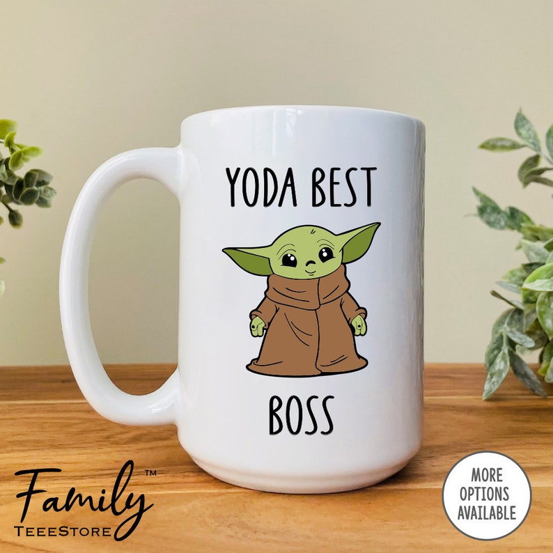 Pu&ograve; includere: Tazza in ceramica bianca con un manico grande, con un'immagine a cartoni animati di Grogu, noto anche come Baby Yoda, con un mantello marrone. Il testo "YODA BEST BOSS" &egrave; stampato sopra e sotto il personaggio in nero.