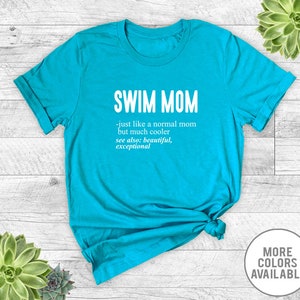 May include: A turquoise blue t-shirt with the text "SWIM MOM - just like a normal mom but much cooler see also: beautiful, exceptional" printed in white.