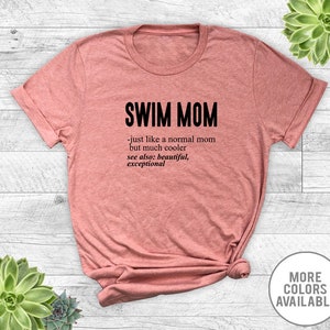 May include: A pink t-shirt with the text "SWIM MOM - just like a normal mom but much cooler see also: beautiful, exceptional" printed in black.