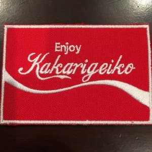 May include: Red fabric patch with white embroidered text that says "Enjoy Kakarigeiko".
