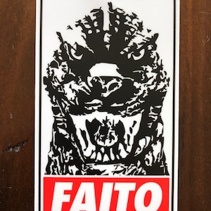 May include: Black and white sticker with a Godzilla-like monster with a large mouth and sharp teeth. The monster's face is in the center of the sticker. The text "FAITO" is in red letters at the bottom of the sticker.