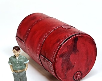 Peut inclure: Un baril en métal rouge avec une apparence légèrement patinée. Le baril est couché sur le côté et a une petite ouverture carrée à l'extrémité.