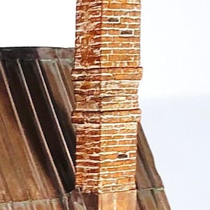 May include: A brick chimney with a brown and white color scheme. The chimney is made of individual bricks stacked on top of each other. The chimney is part of a roof.