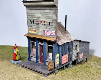 May include: A miniature model of a rustic wooden general store with a sign that reads "Standard Mercantile Company". The store has a blue door and windows, a wooden porch, and a barrel in front. There are several vintage advertisements on the side of the building, including "Old Gold" and "Pepsi Cola".