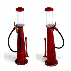 K&ouml;nnte beinhalten: Zwei Miniatur-Zapfs&auml;ulen in Rot mit einem Used-Look. Jede Pumpe hat einen transparenten Glaszylinder, einen schwarzen Schlauch und eine Messingd&uuml;se. Die Pumpen stehen vor wei&szlig;em Hintergrund.