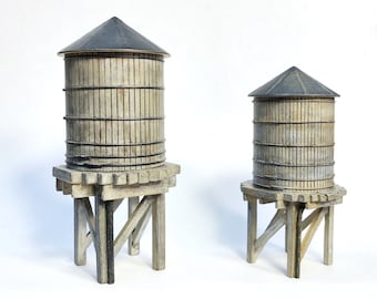 Könnte beinhalten: Zwei hölzerne Wassertürme mit grauen Dächern. Der größere Turm befindet sich links und der kleinere rechts. Beide Türme stehen auf Holzständern.