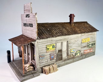 May include: A weathered wooden building with a sign that reads "Apex Seed & Feed". The building has a rusty metal roof and several signs advertising various products, including "Cats Paw", "Fincks Diesel", "Haley Barley", and "Cambridge Steel Plows".
