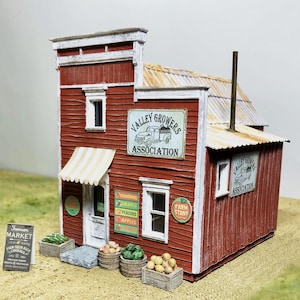 May include: A miniature red wooden farm stand with a white awning and signs that read "Valley Growers Association" and "Farm Stand." The stand has a sign that says "Farmer's Market" and displays of produce.