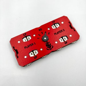 May include: Red and black game tracker with a skull icon. The tracker has two sections, one for each player, with spaces for points, control points, and rounds. The tracker has a rotating dial with numbers 1 through 5.