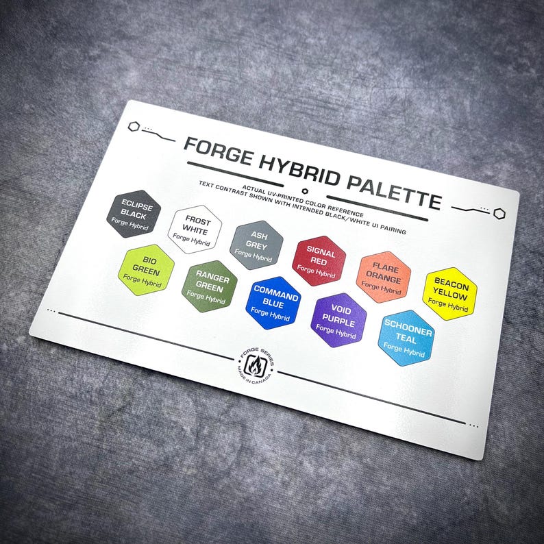 Puede incluir: Una tarjeta de referencia rectangular blanca Forge Hybrid Palette que presenta diez muestras de color hexagonales etiquetadas como Eclipse Black, Frost White, Ash Grey, Signal Red, Flare Orange, Beacon Yellow, Bio Green, Ranger Green, Command Blue, Void Purple y Schooner Teal.