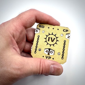 May include: A wooden game tracker with a gold finish. The tracker has a sunburst design with the Roman numeral IV in the center. The tracker has a number of dials, including RD, CP, VP, and 40.