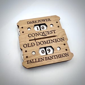 May include: Wooden game board with the words "DARK POWER", "CONQUEST", "OLD DOMINION", and "FALLEN PANTHEON" etched into the wood. The board has two windows displaying the numbers 10 and 09. A sword graphic is between "CONQUEST" and "OLD DOMINION".