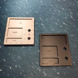 May include: Two wooden game trays, one in beige and one in black, with compartments labelled "Orders", "L-R-S", and "D10".