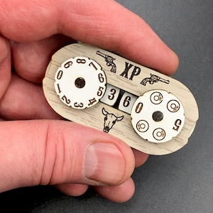 May include: Wooden counter with a skull, two pistols, and a number dial that reads "XP 360". The counter also has a circular dial with numbers 1 through 8 and a smaller circular dial with five bullet holes.