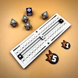 May include: A white wooden board with a sliding scale marked with numbers 1 through 9. The board is used for a game with dice. There are several grey dice with white symbols on them and a blue die with a white symbol on it. There are also two orange and black tokens with the numbers 1 and 5 on them.