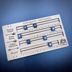 May include: A wooden game board with a brown background and red lines. The board has four rows labeled "Victory Points", "Dark Power", "Fallen Pantheon", and "Round". Each row has a number scale from 0 to 20. There are blue markers on the board indicating scores.