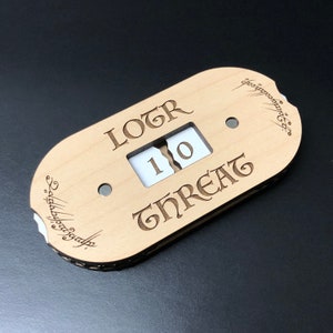 May include: A wooden counter with a dial that reads "LOTR Threat 10". The counter is decorated with an inscription in Elvish script.