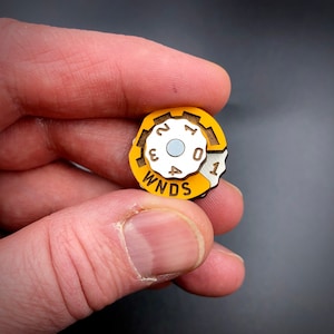 May include: A yellow and white wooden knob with numbers 0-4 and the word "WNDS" printed on it.